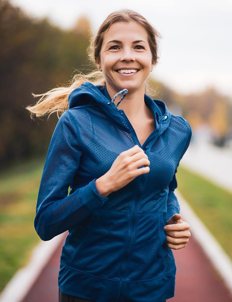 Beautiful adult woman is jogging outdoor on cloudy day in autumn